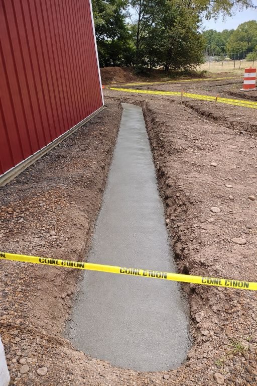Concrete footer trench drain installation next to commercial building in New Jersey